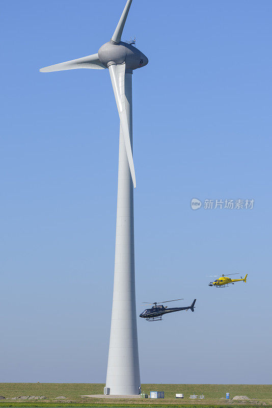 欧洲直升机公司AS355N Ecureuil 2直升机绕着一个大型风力涡轮机飞行